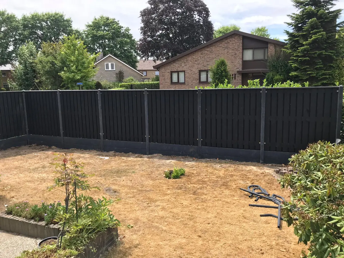 Zwarte houten schutting met antracieten betonpalen
