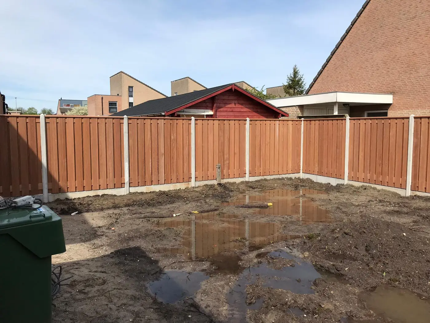 Hardhouten schutting met betonnen palen en onderplaten
